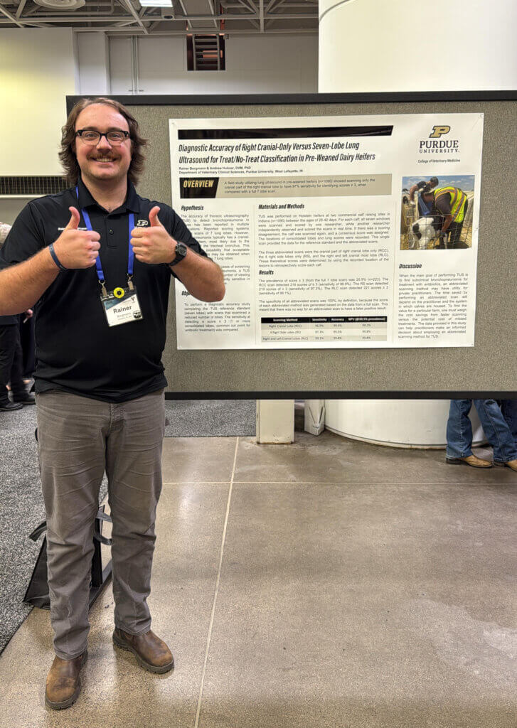 A man is giving two 'thumbs up' signs and is standing in front of a poster that is titled "Diagnostic Accuracy of Right Cranial-Only Versus Seven-Lobe Lung Ultrasound for Treat/No-Treat Classification in Pre-Weaned Dairy Heifers"