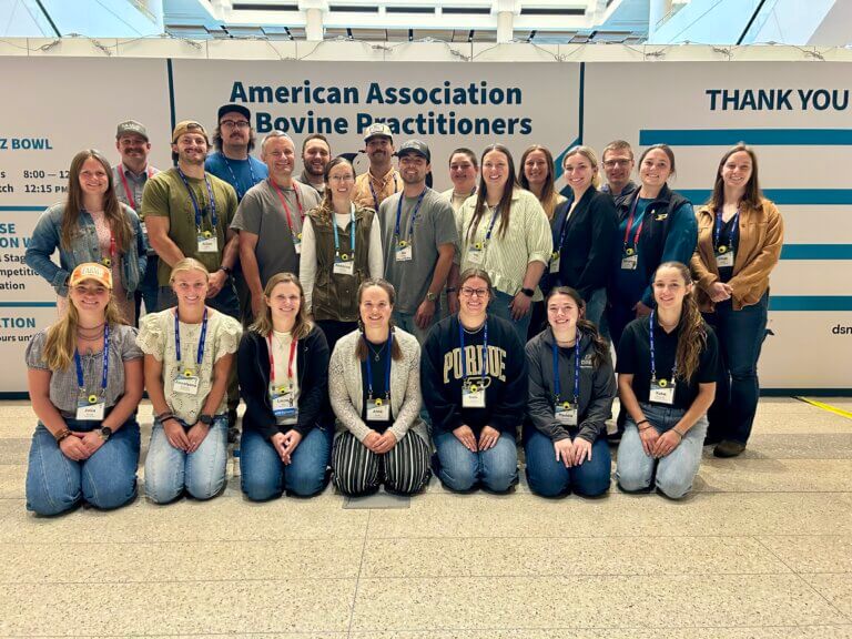 A large group of people are positioned for a photo in front of a sign that says "American Association of Bovine Practitioners"