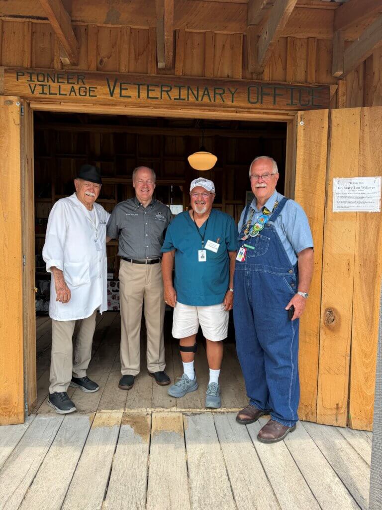 Four men are standing in a barn doorway.