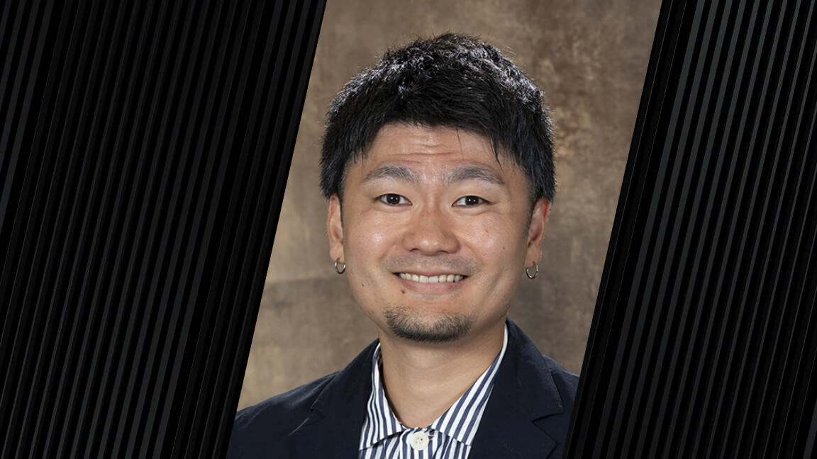 portrait of a man with dark hair, wearing a button-up striped shirt and dark colored jacket
