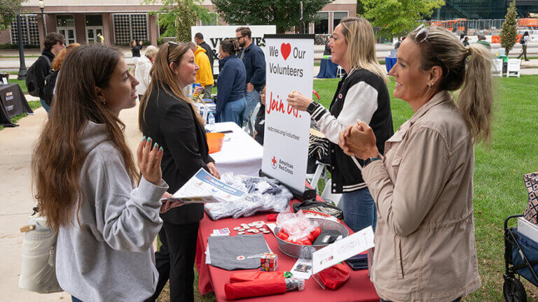 Women appear to be speaking across a booth at an outdoor event