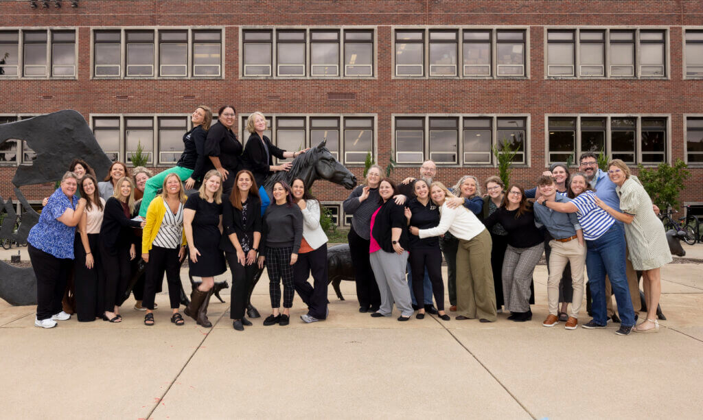 A large group of people are standing around an outdoor animal sculpture