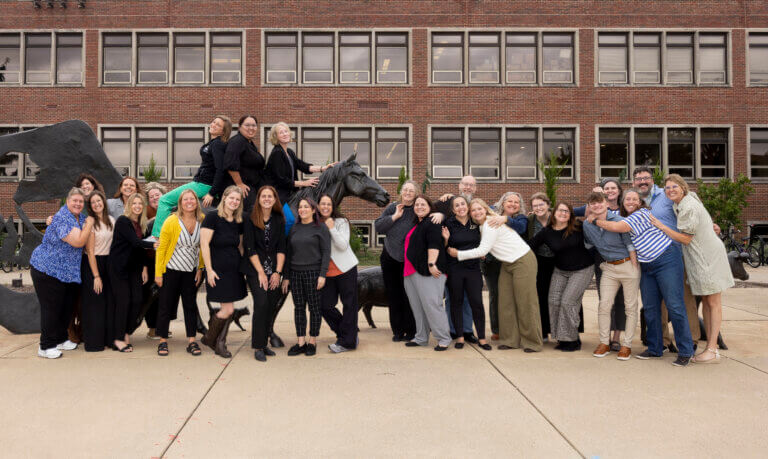 A large group of people are standing around an outdoor animal sculpture