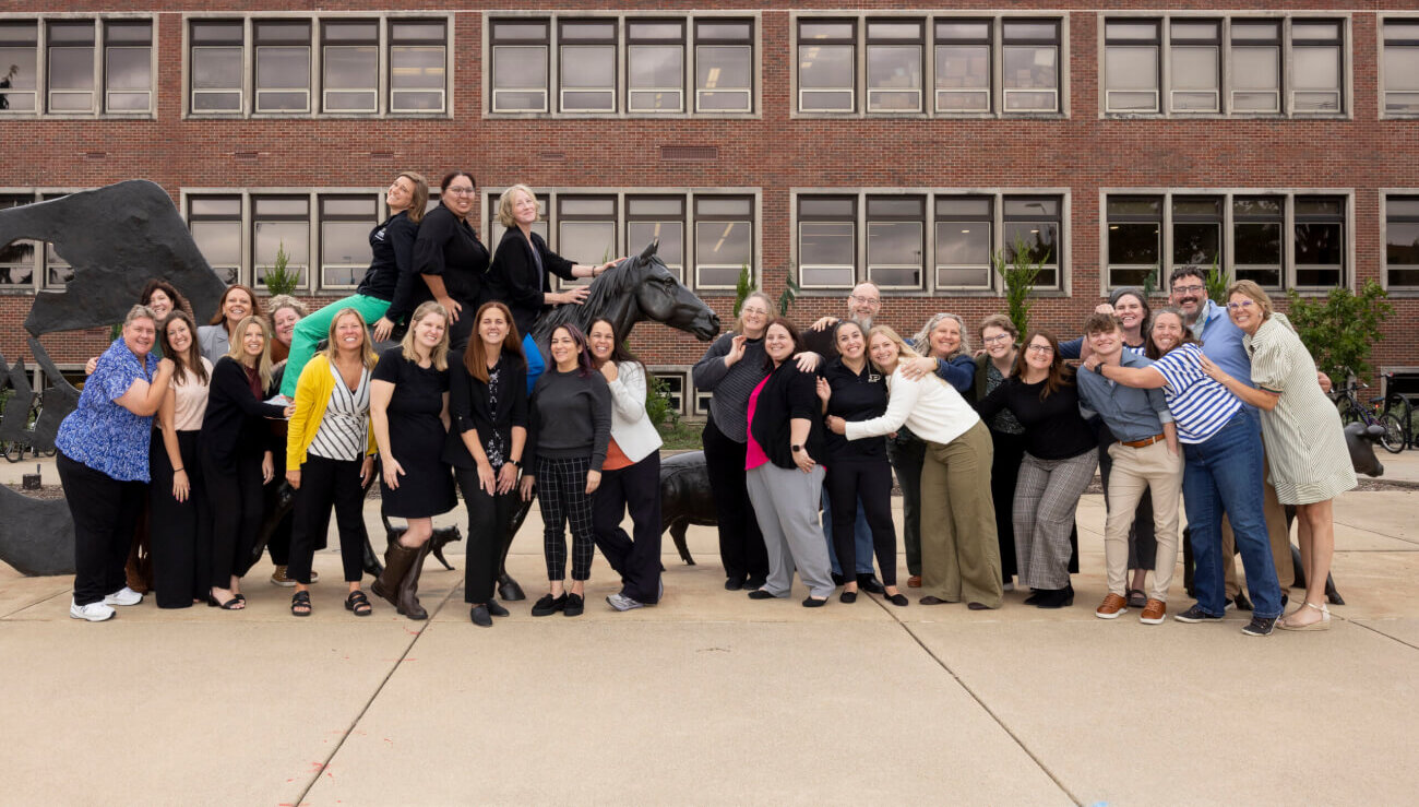A large group of people are standing around an outdoor animal sculpture