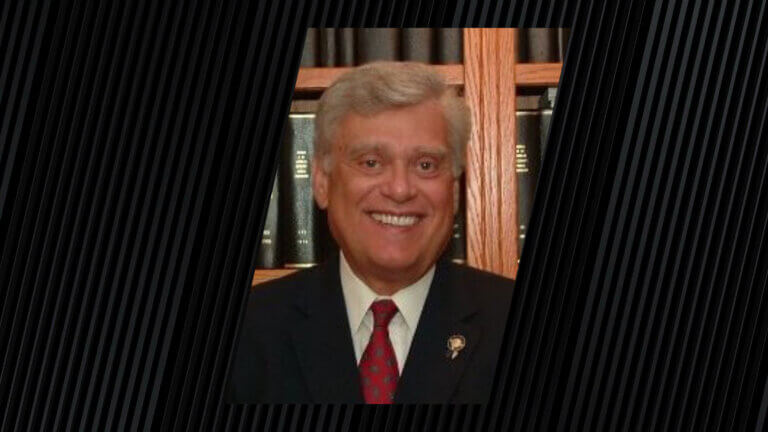 portrait of a person wearing a red tie and a dark suit jacket