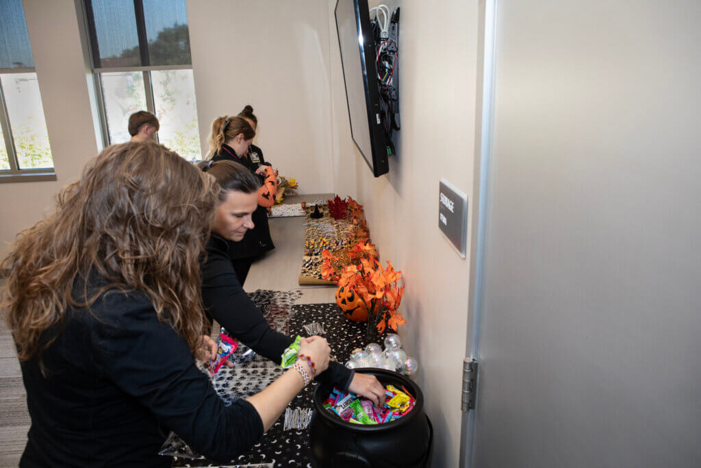 There are various halloween-themed treats sitting on a table with people grabbing them