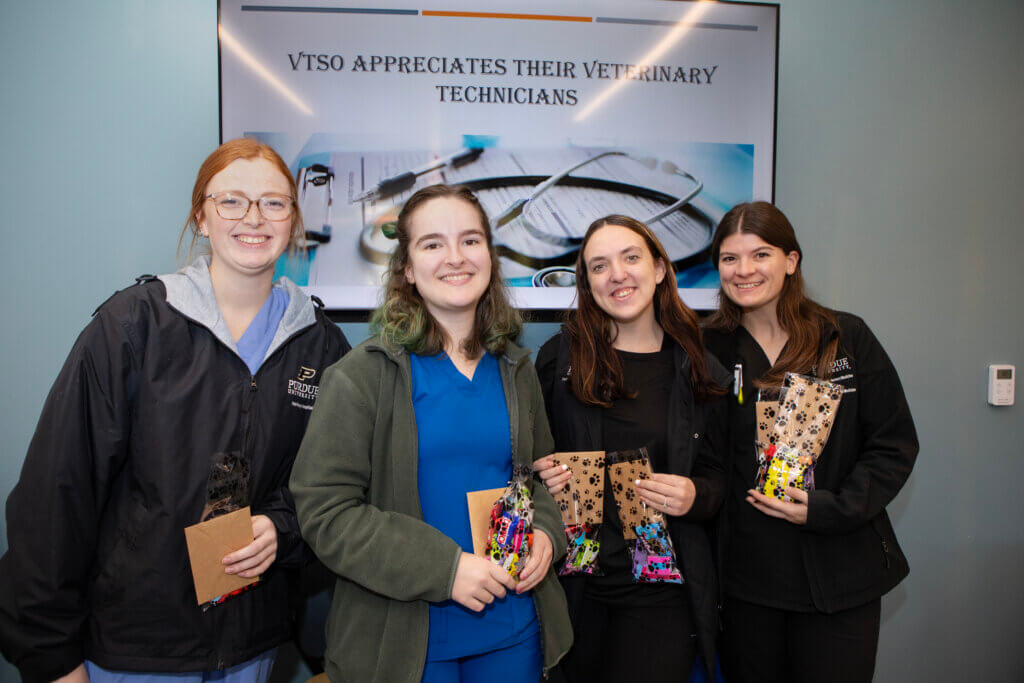 A group of four people are gathered together holding snacks and candy.