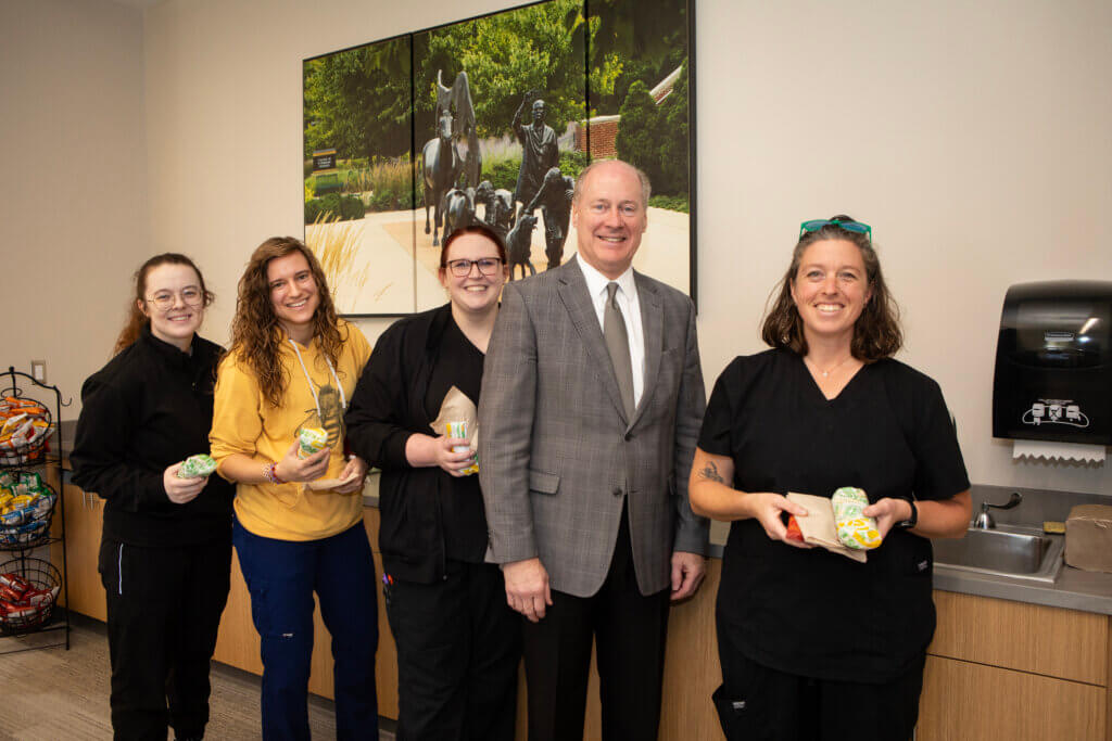 Several people are standing in front of a countertop and holding subway sandwiches