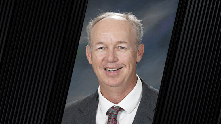 portrait of a man wearing a red patterned tie and a gray suit jacket