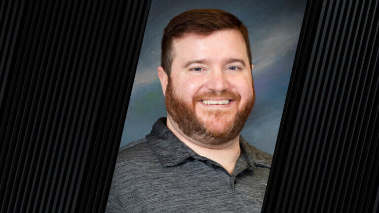 portrait of a person with short, dark hair, wearing a gray collared shirt