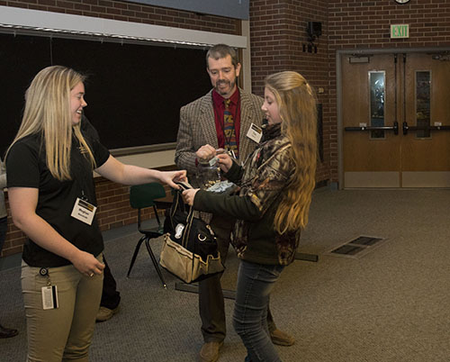 Equine Club President Meghan Wanstrath, of the DVM Class of 2019, awards a give-away to Dakota Szakacs, a horse enthusiast in the 7th grade from St. Joseph County, as Dr. Tim Lescun looks on during the Horseman's Forum in Lynn 1136.