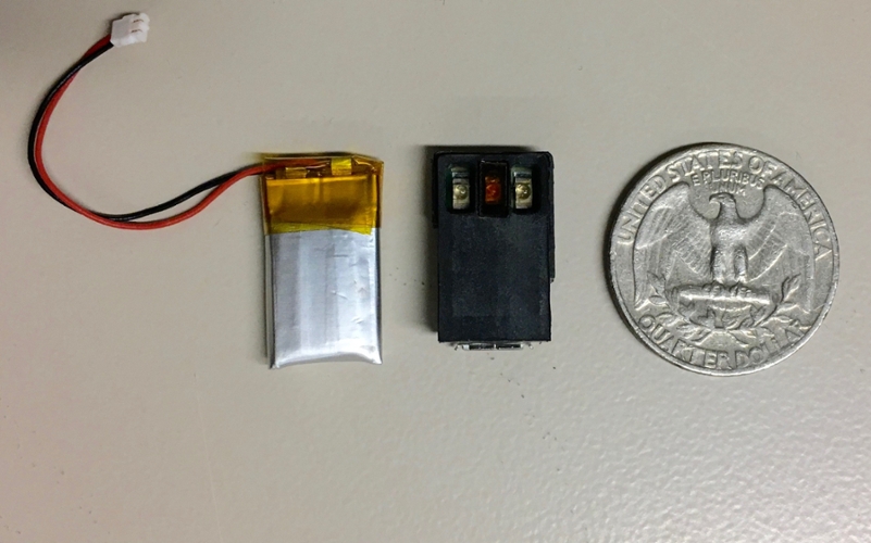 Fig. 1 The NIC Kidney device with battery (left) in comparison to a quarter dollar coin. The device is small and lightweight.