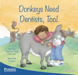 A child hugs a friendly donkey while smiling in a grassy outdoor setting.