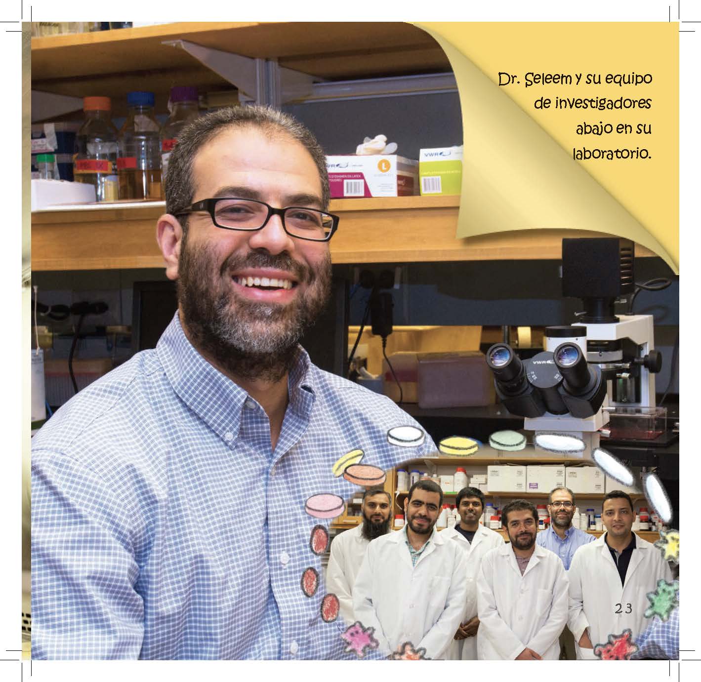 A smiling researcher stands in a laboratory with his team pictured behind him.
